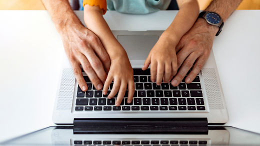 Hands of parent and child on a computer